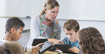 A teacher working with her students on their tablets.