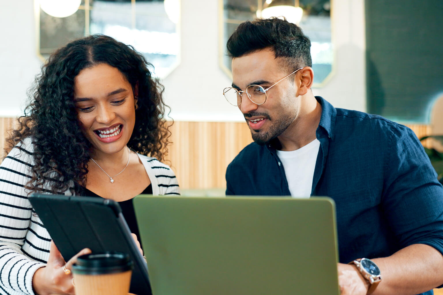 Two coworkers looking at laptops and tablets. 