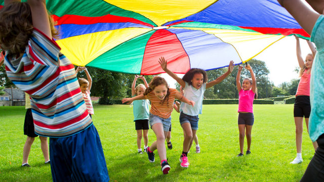 Students playing with a parachute outside.