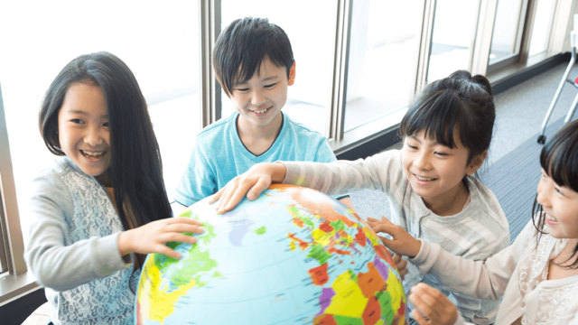 Smling students studying a globe.